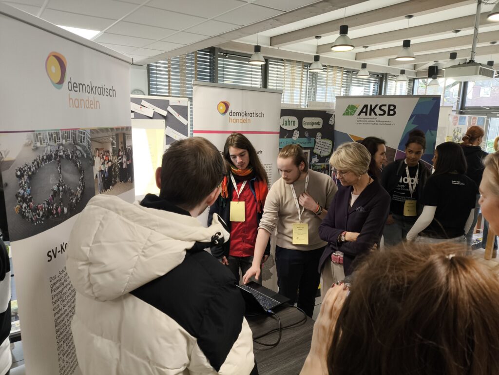 Messebesucher in einem Ausstellungsraum, die Informationen an einem Stand besprechen.