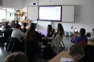 Schüler sitzen im Klassenraum und schauen auf einen Projektor.