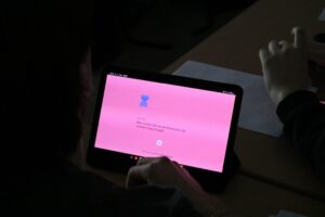 Schüler arbeitet an einem Tablet mit pinkem Bildschirm.