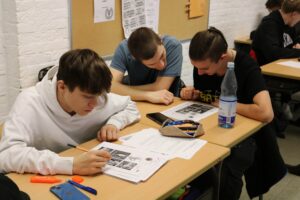 Schüler arbeiten konzentriert an Aufgaben an einem Tisch.