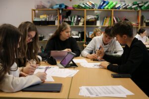 Schüler arbeiten gemeinsam an Aufgaben an einem Tisch.