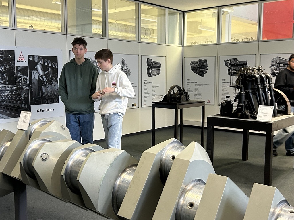 Schüler betrachten einen großen Motorenbauteil in einem Ausstellungsraum.