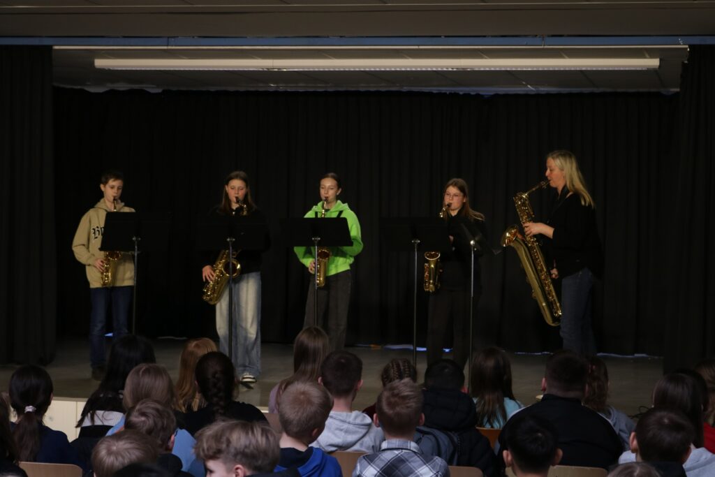 Schüler spielen Saxophon auf einer Bühne vor einem Publikum.
