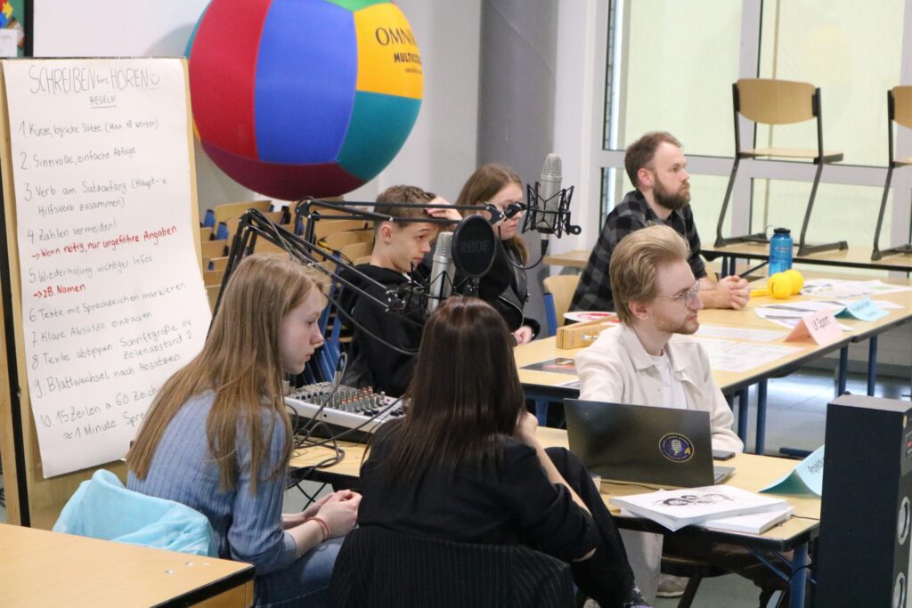 Schülerinnen und Schüler sitzen an Tischen und arbeiten an Projekten im Klassenzimmer.
