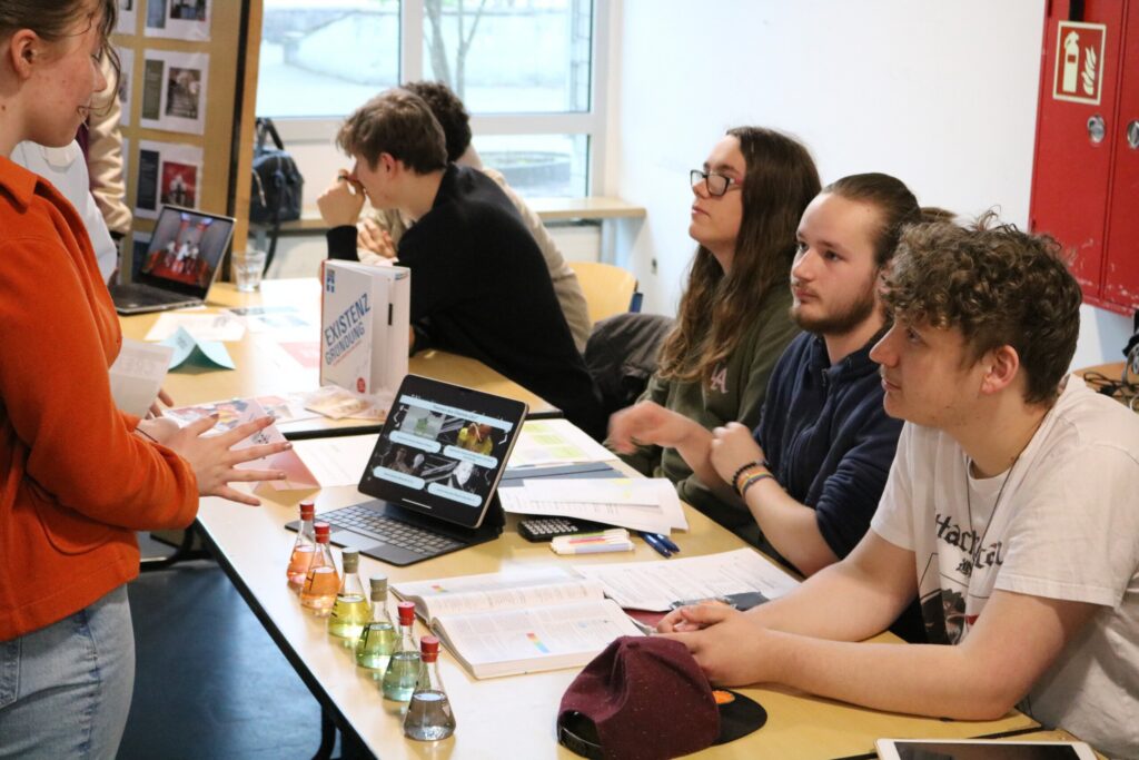 Schüler präsentieren an einem Tisch verschiedene Projekte und Materialien.