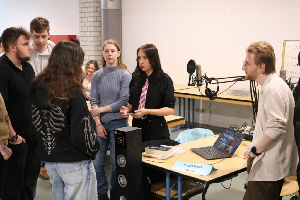 Schüler präsentieren ein Projekt und diskutieren an einem Tisch.
