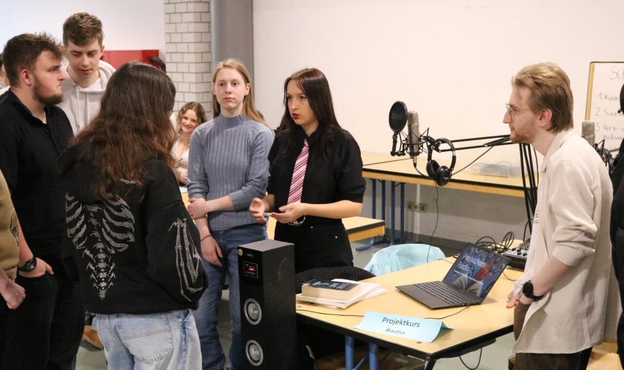 Schüler präsentieren ein Projekt und diskutieren an einem Tisch.