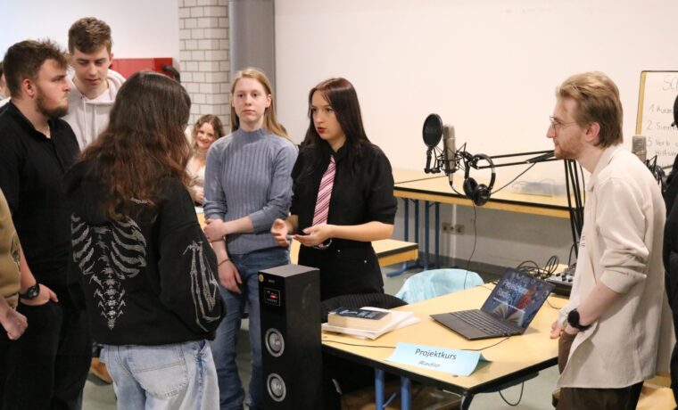 Schüler präsentieren ein Projekt und diskutieren an einem Tisch.