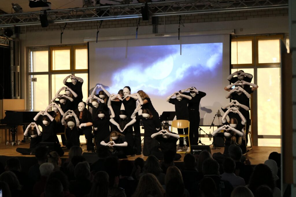 Schüler führen eine Tanz- oder Theateraufführung auf einer Bühne vor.