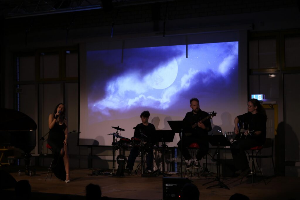Musiker spielen auf der Bühne, im Hintergrund eine Projektion von Wolken.