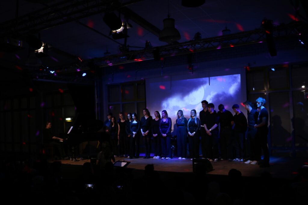 Schüler treten auf einer Bühne bei einem musikalischen Event auf.