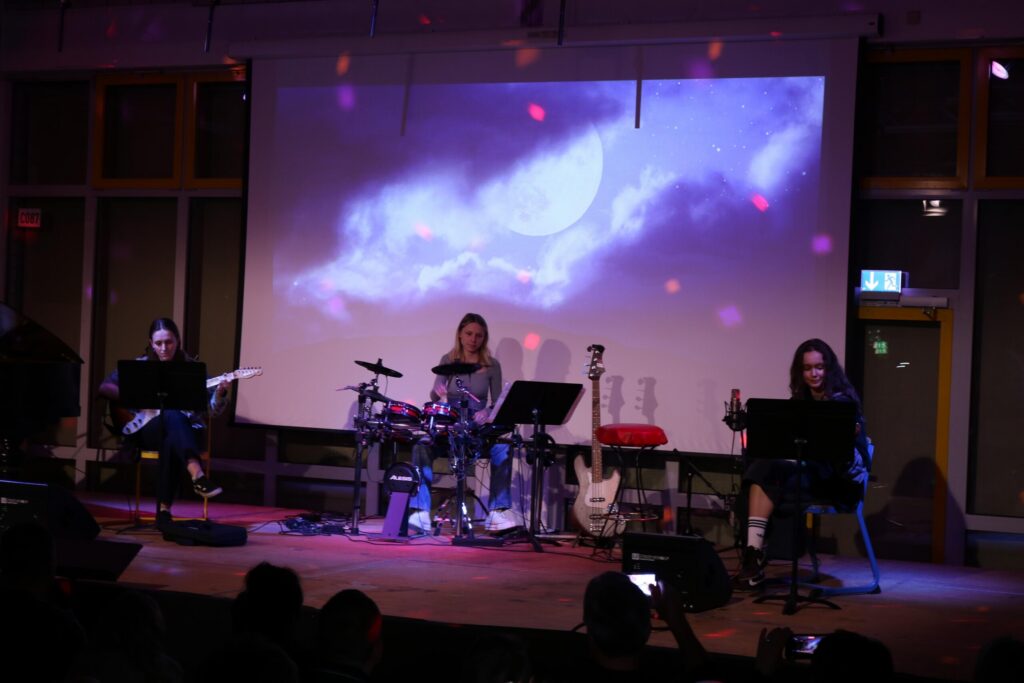 Band spielt live auf der Bühne vor einer projizierten Wolkenlandschaft.