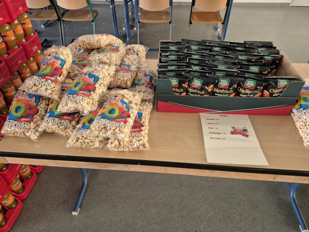 Tisch mit Popcorn und Getränkekartons in einer Schulumgebung.