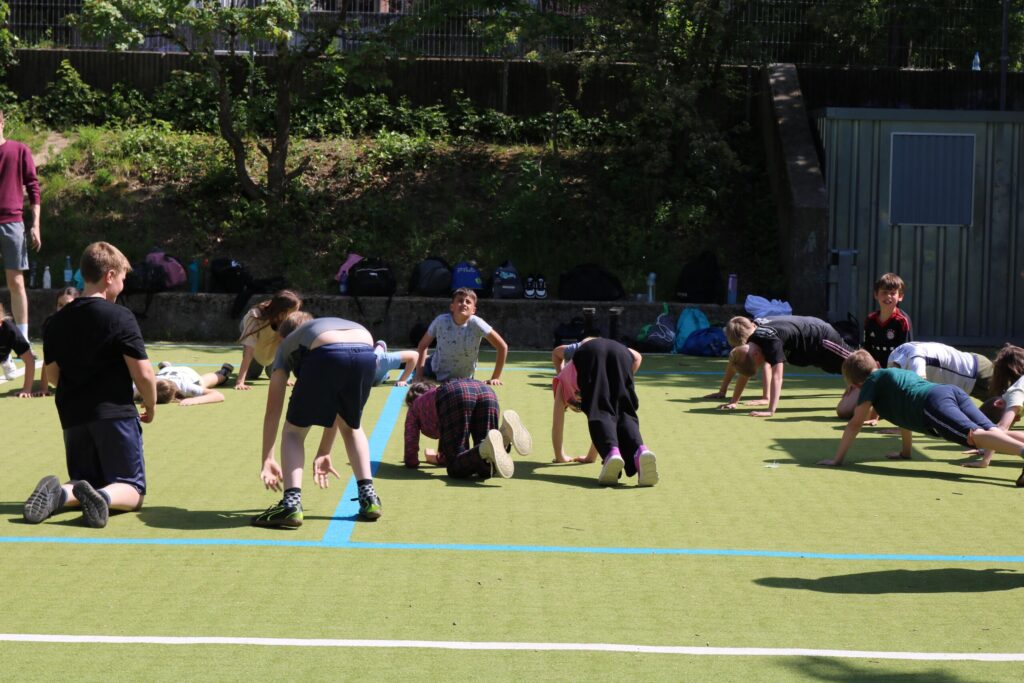 Schüler machen Sportübungen auf einem Sportplatz.