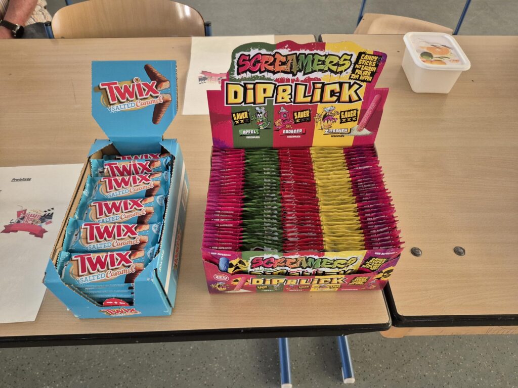 Candy-Box mit Twix-Riegeln und bunten Dip & Lick Süßigkeiten auf einem Tisch.