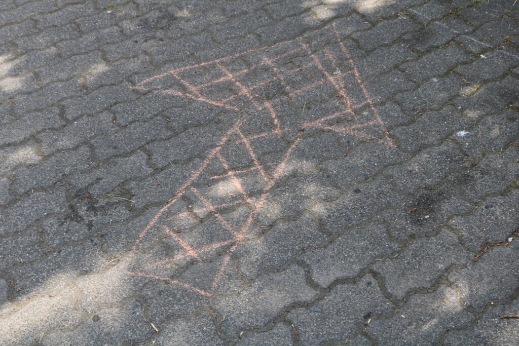 Pfeil aus Kreide auf einem gepflasterten Boden.