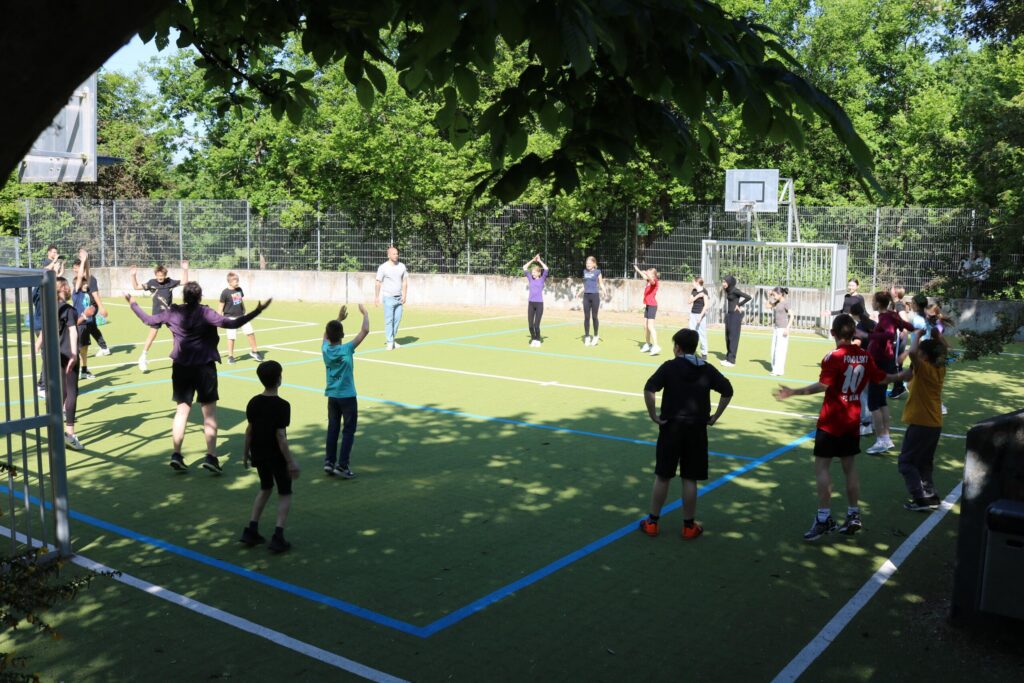 Gruppe von Schülern spielt im Freien auf einem Sportfeld.