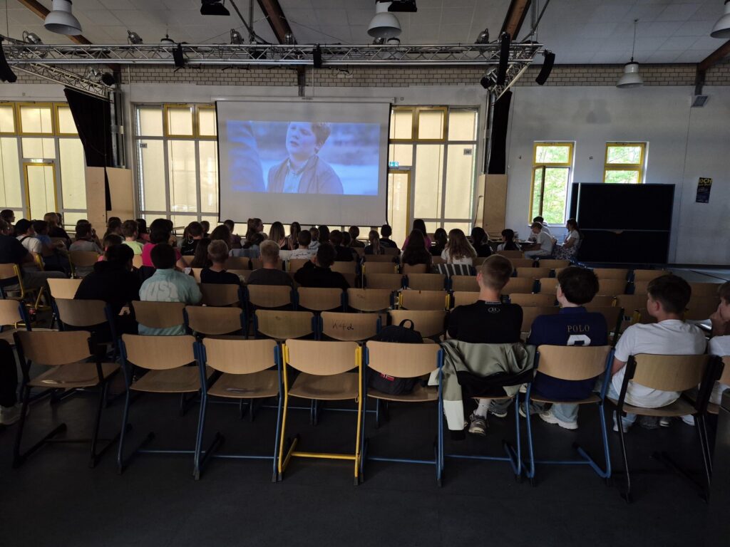 Schüler sitzen im Zuschauerraum und schauen einen Film auf großer Leinwand.