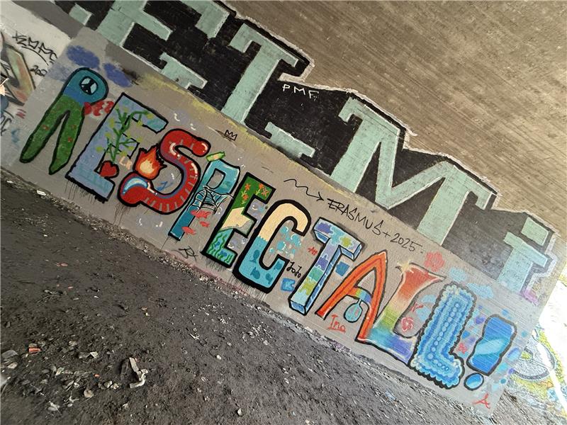 Graffiti mit dem Wort "RESPECT" in bunten Farben unter einer Brücke.
