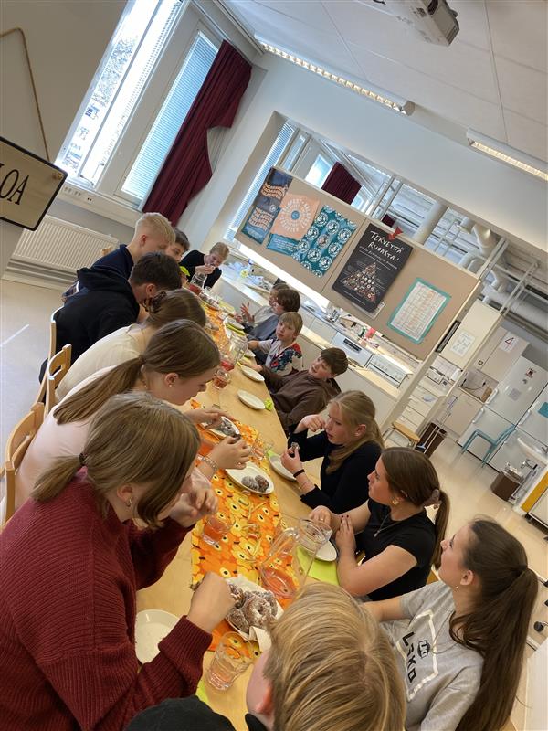 Schüler sitzen an einem Tisch und essen gemeinsam.