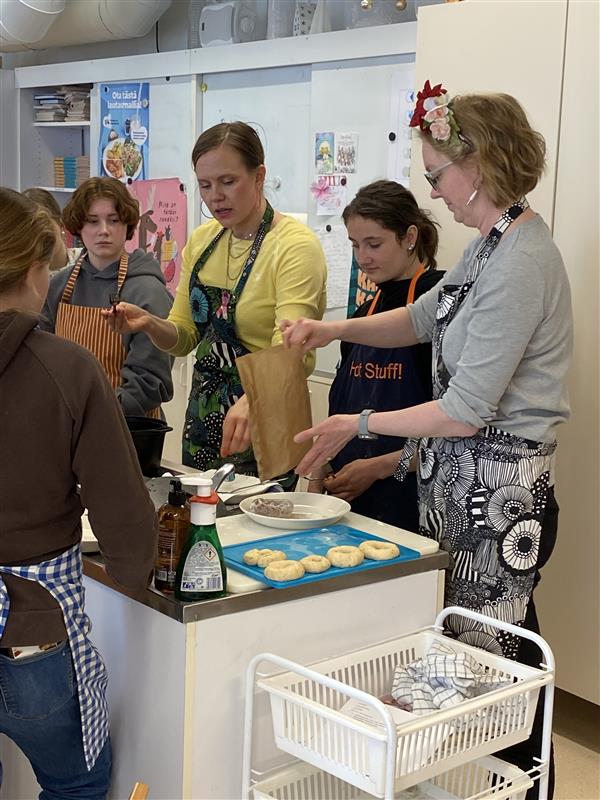 Schüler und Lehrkräfte, die in einer Küche gemeinsam kochen und arbeiten.
