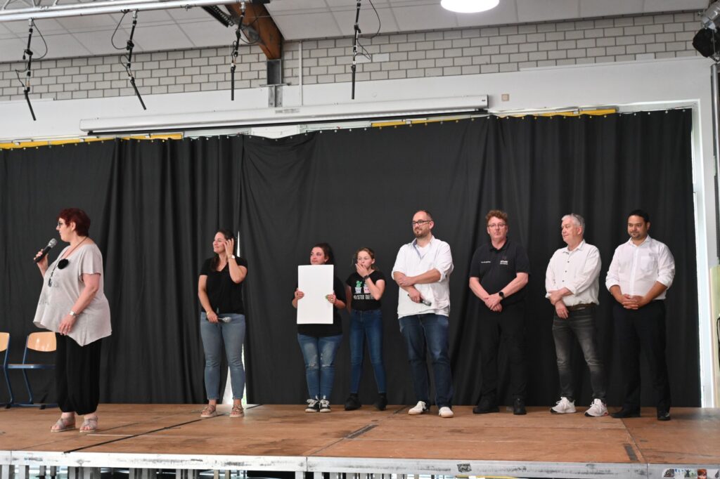 Ein Team steht auf einer Bühne während einer Veranstaltung.