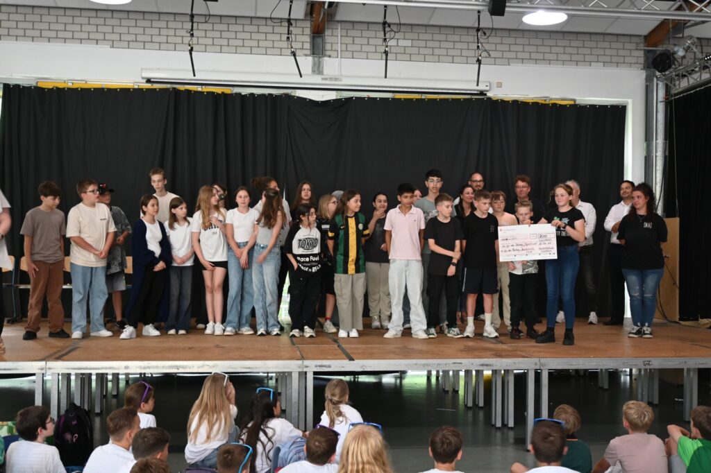 Schülerinnen und Schüler stehen auf der Bühne während einer Veranstaltung.