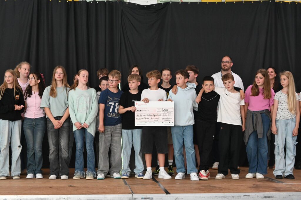 Schüler stehen auf einer Bühne und halten ein Plakat.