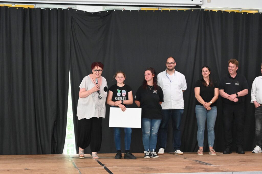 Eine Gruppe von Personen auf einer Bühne mit einer Präsentation.
