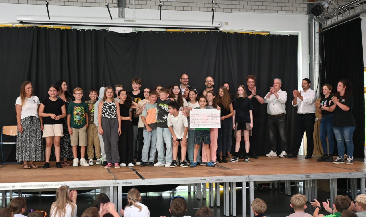 Gruppenszene auf einer Bühne mit Schülern und Lehrern bei einer Veranstaltung.