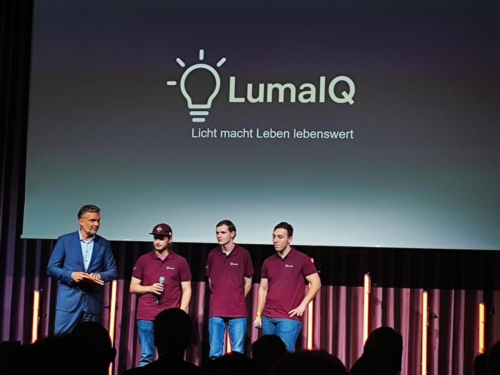 Präsentation eines Teams mit einem Logo von LumalQ im Hintergrund.