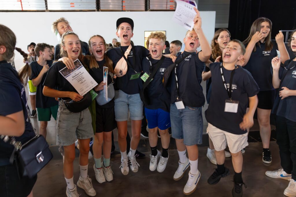 Jubelnde Schüler:innen der Bläserklasse 7d direkt nach der Siegerehrung – mit Urkunden in den Händen und breitem Lachen im Gesicht feiern sie ihren ersten Platz beim BW Musix-Wettbewerb.