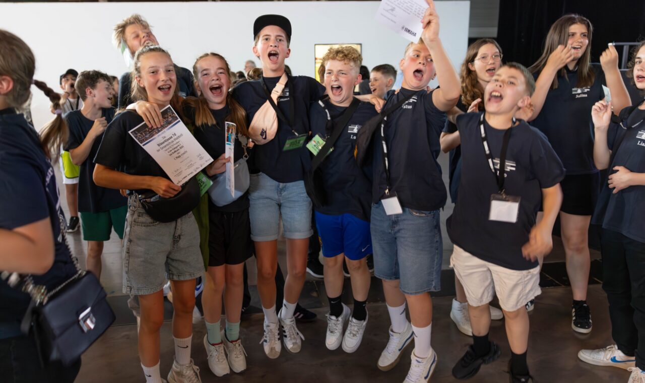 Jubelnde Schüler:innen der Bläserklasse 7d direkt nach der Siegerehrung – mit Urkunden in den Händen und breitem Lachen im Gesicht feiern sie ihren ersten Platz beim BW Musix-Wettbewerb.
