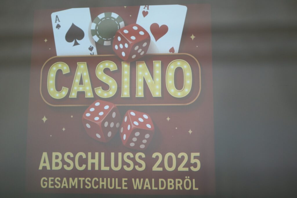 Nahaufnahme der projizierten Motto-Grafik „Casino – Abschluss 2025 Gesamtschule Waldbröl“ mit Spielkarten, Würfeln und Pokerchip als Gestaltungselemente.