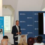 Begrüßung durch Ingo Stockhausen, Vorstandsvorsitzender der Volksbank Oberberg, bei der Verleihung des Berufswahl-Siegels 2025. Im Hintergrund Banner der kommunalen Koordinierungsstelle und Logos der Volksbank.