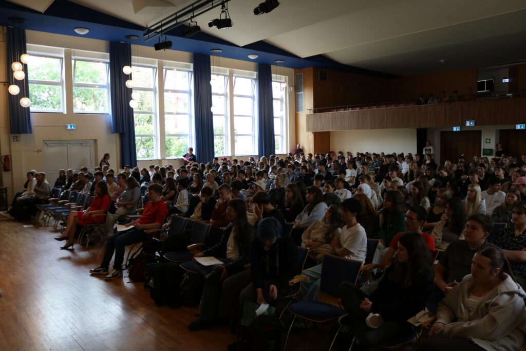 Rund 350 Schüler:innen der Jahrgangsstufe 10 sowie der Oberstufe verfolgen aufmerksam die Podiumsdiskussion.