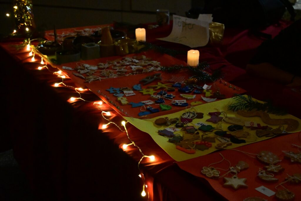 Tisch mit selbstgebastelten Weihnachtsdekorationen und Anhängern, Kerzen und Lichterkette sorgen für warme Beleuchtung.