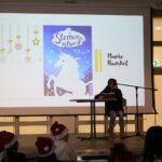 Schülerin liest am Mikrofon; im Hintergrund ist das Buchcover „Sternenschweif – Sprung in die Nacht“ auf der Leinwand zu erkennen.