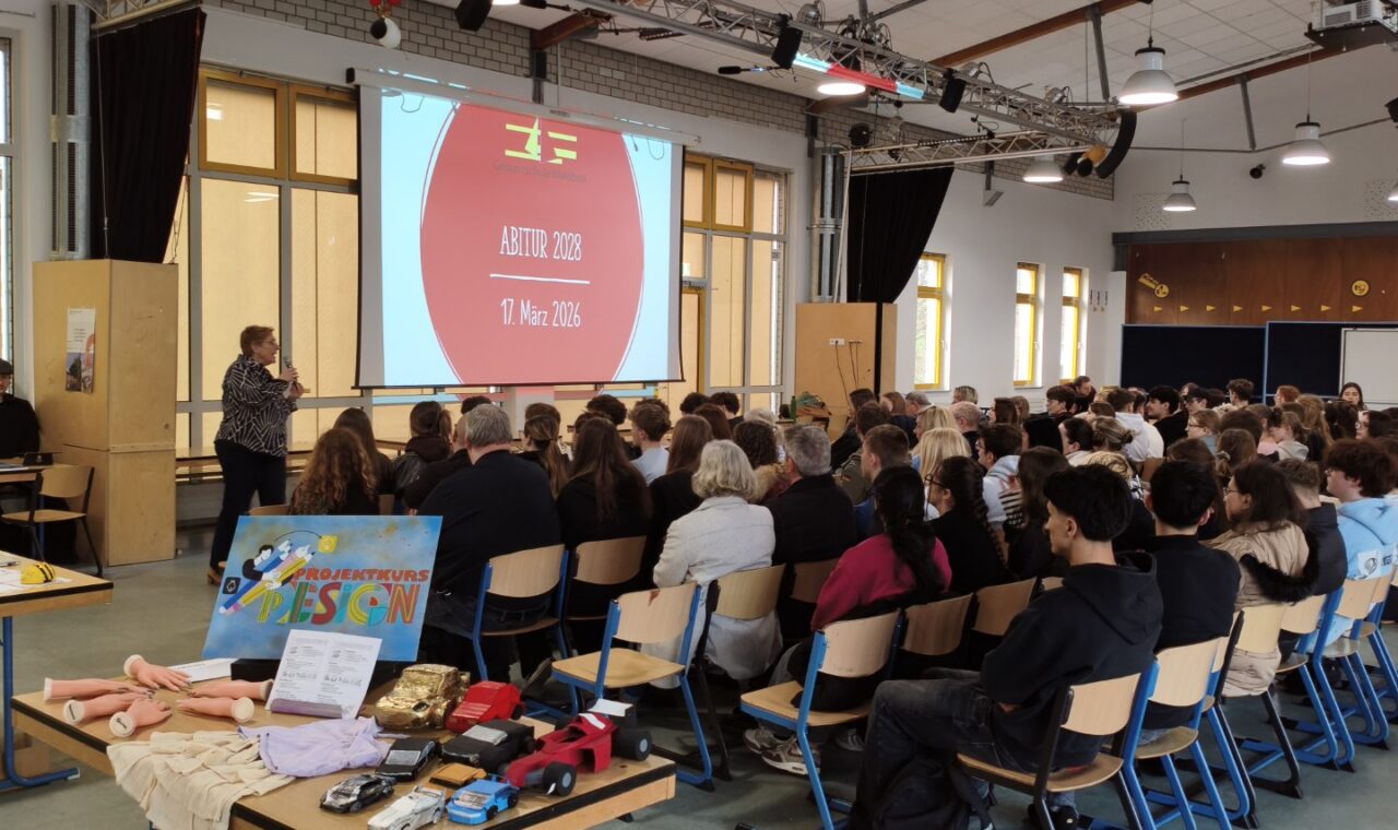 Volle Mensa beim Infoabend: Schüler:innen und Eltern verfolgen die Einführung zur Kurswahl vor einer Präsentation.