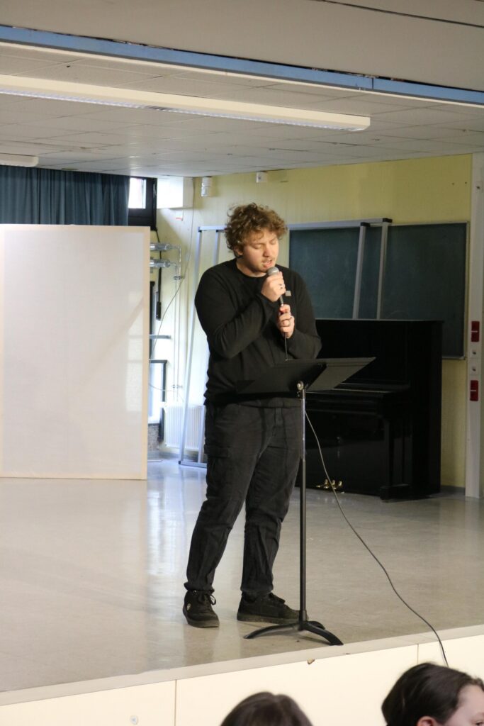 Finn Kalsner steht mit Mikrofon am Notenständer und singt seinen Beitrag bei der Open Stage.