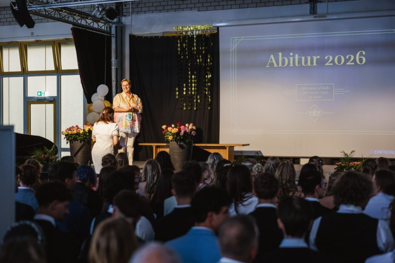 Abiturfeier 2026 mit Redner und Publikum in festlicher Atmosphäre.