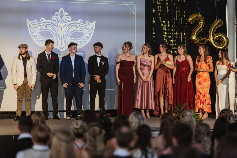 Gruppe von Personen in eleganter Kleidung auf einer Bühne bei einer Feier.