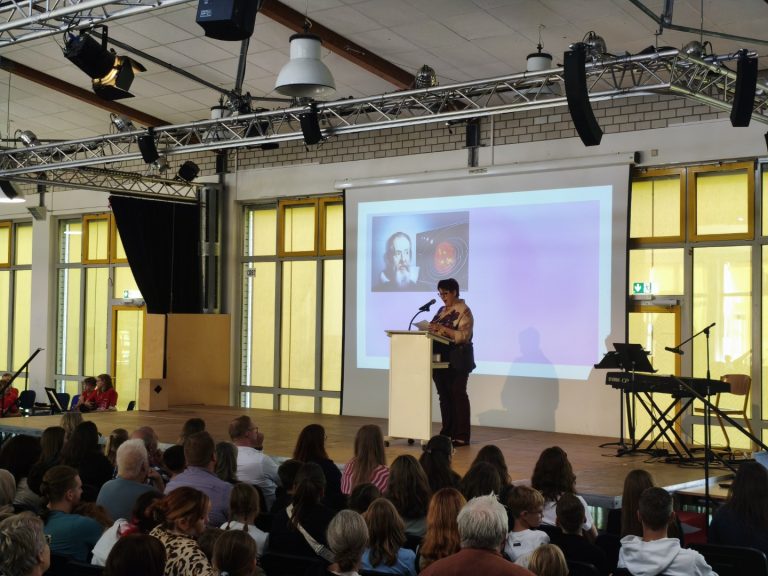 Schüler präsentiert vor Publikum auf einer Bühne mit technischem Equipment.