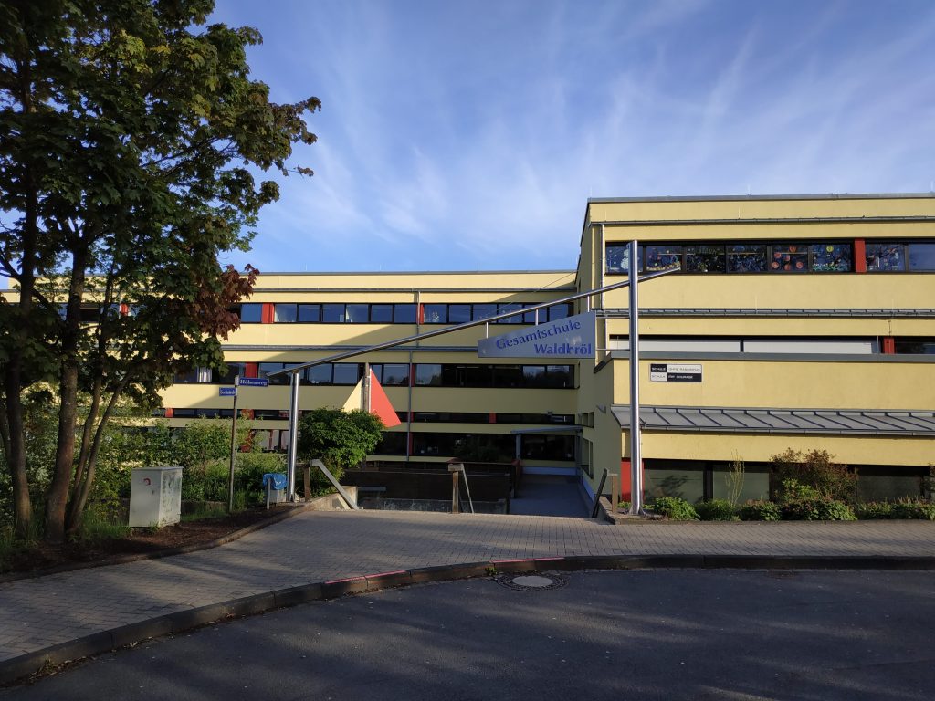 Gesamtschule Waldbrühl mit Eingang und Grünfläche im Vordergrund.