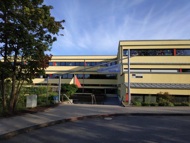 Gesamtschule Waldbrühl mit Eingang und Grünfläche im Vordergrund.