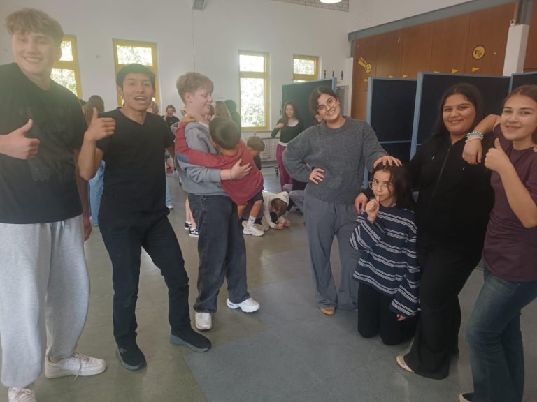 Gruppe von vielen Schülern in einem Klassenraum, einige posieren fröhlich.