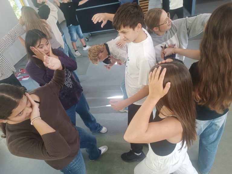 Schülerinnen und Schüler in einer Gruppe, die verschiedene Posen einnehmen.