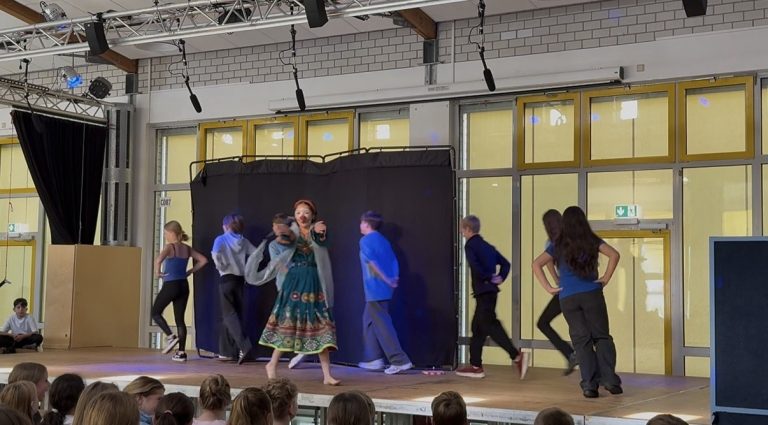 Schüler führen auf der Bühne ein Tanzstück vor. Bühne mit schwarzer Kulisse.