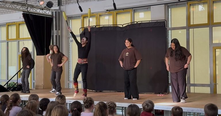 Aufführung auf der Bühne mit fünf Darstellern in braunen T-Shirts.