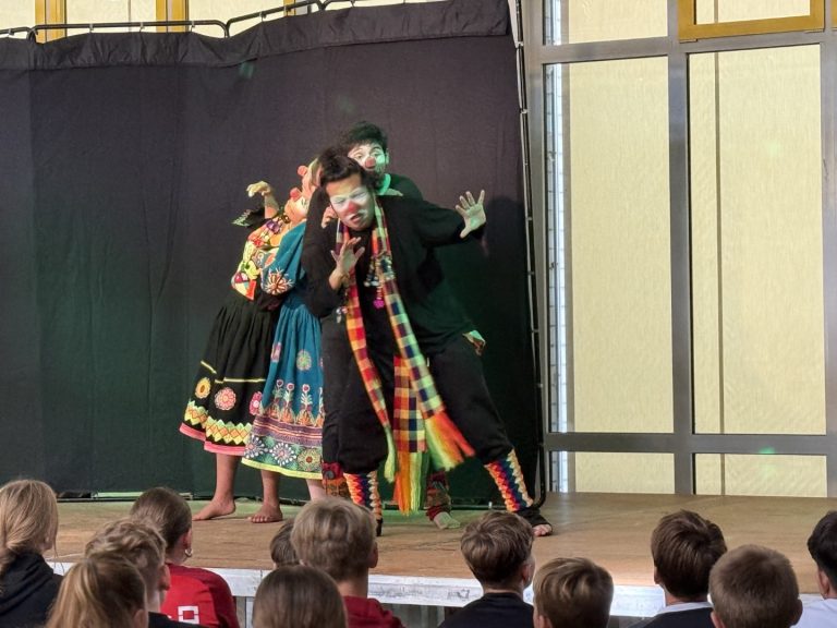 Aufführung mit schauspielenden Personen in bunten Kostümen auf einer Bühne.